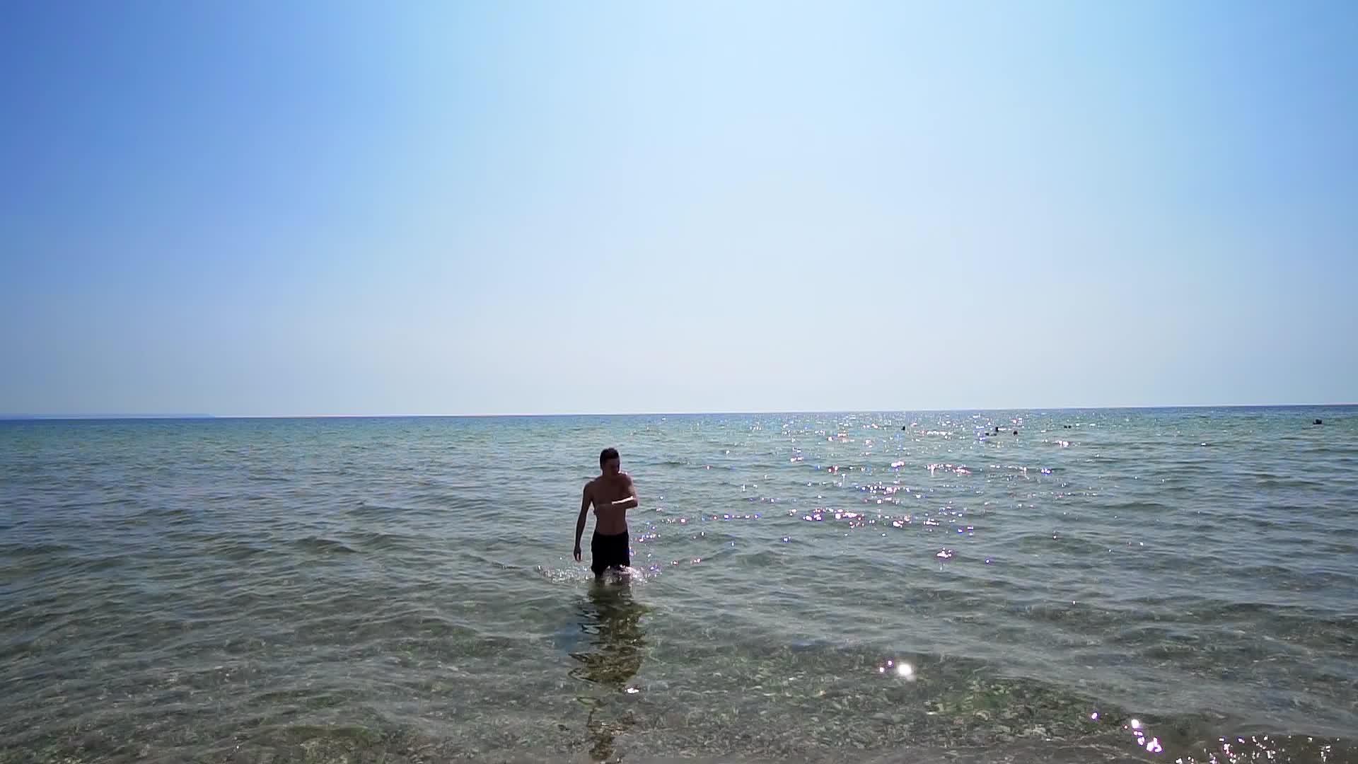帅帅的男运动员从海边的水里出来拍电影慢动作视频的预览图