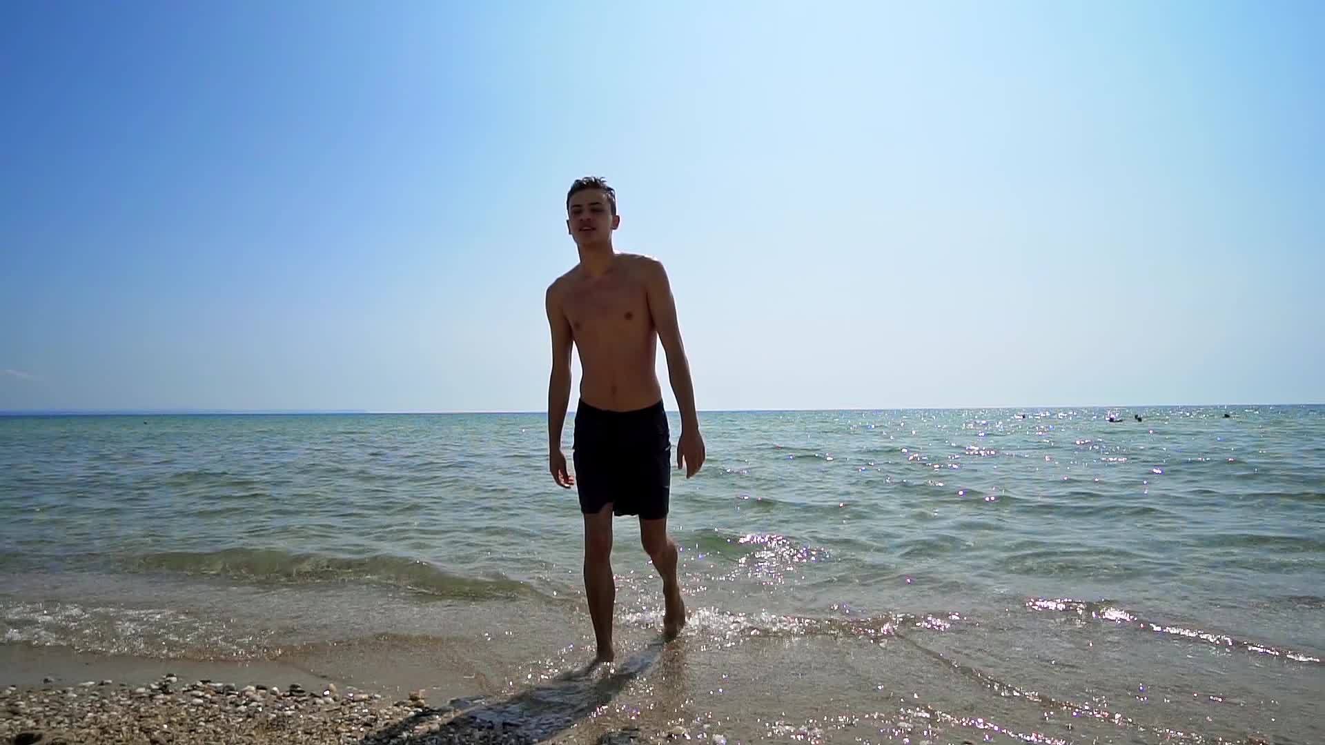 帅帅的男运动员从海边的水里出来拍电影慢动作视频的预览图