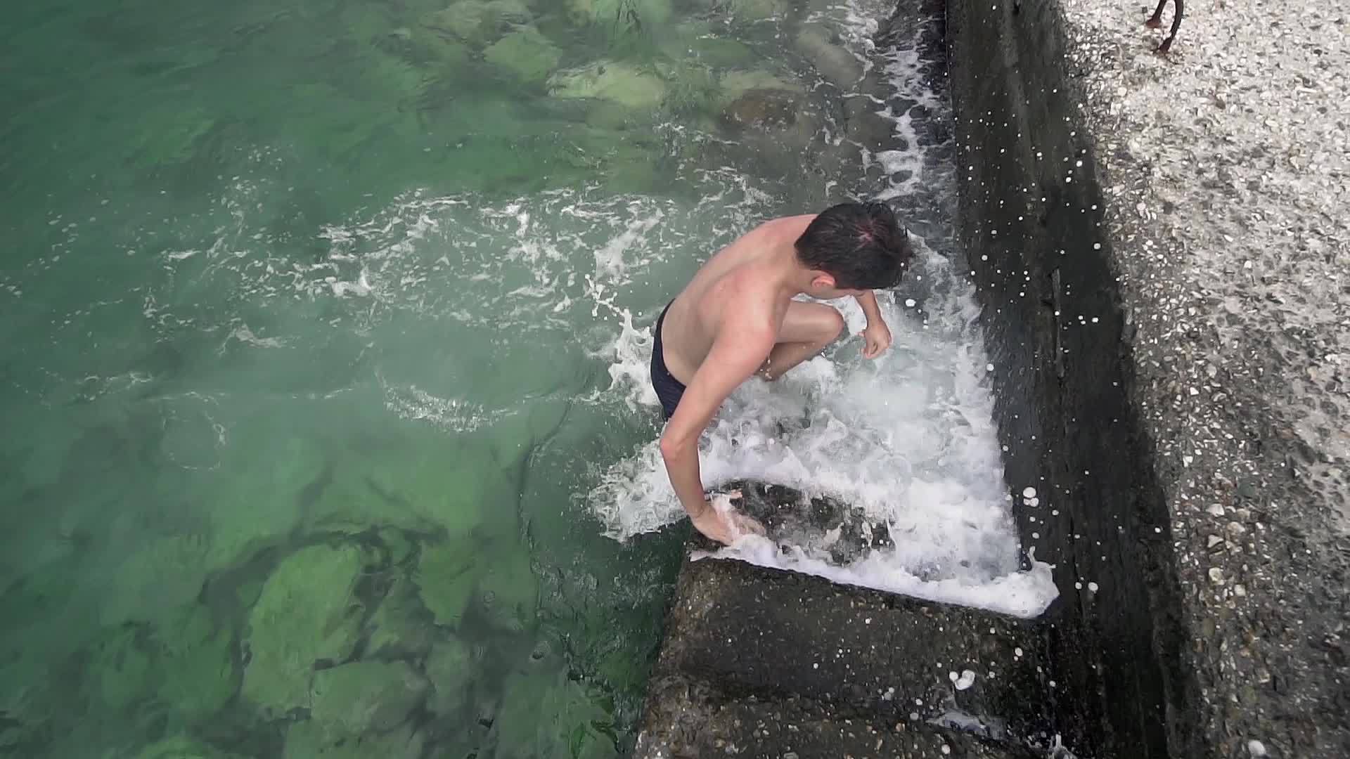 游泳后在码头混凝土楼梯上出海的帅哥少年视频的预览图