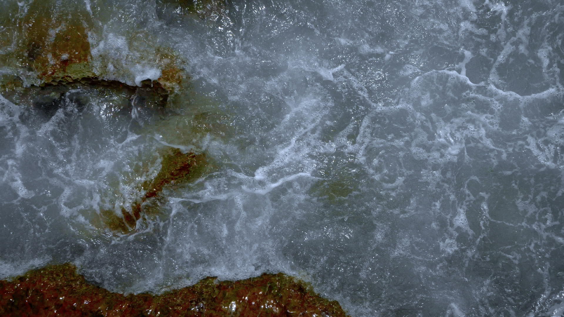 在岩石上喷洒自然背景的海水泡沫视频的预览图