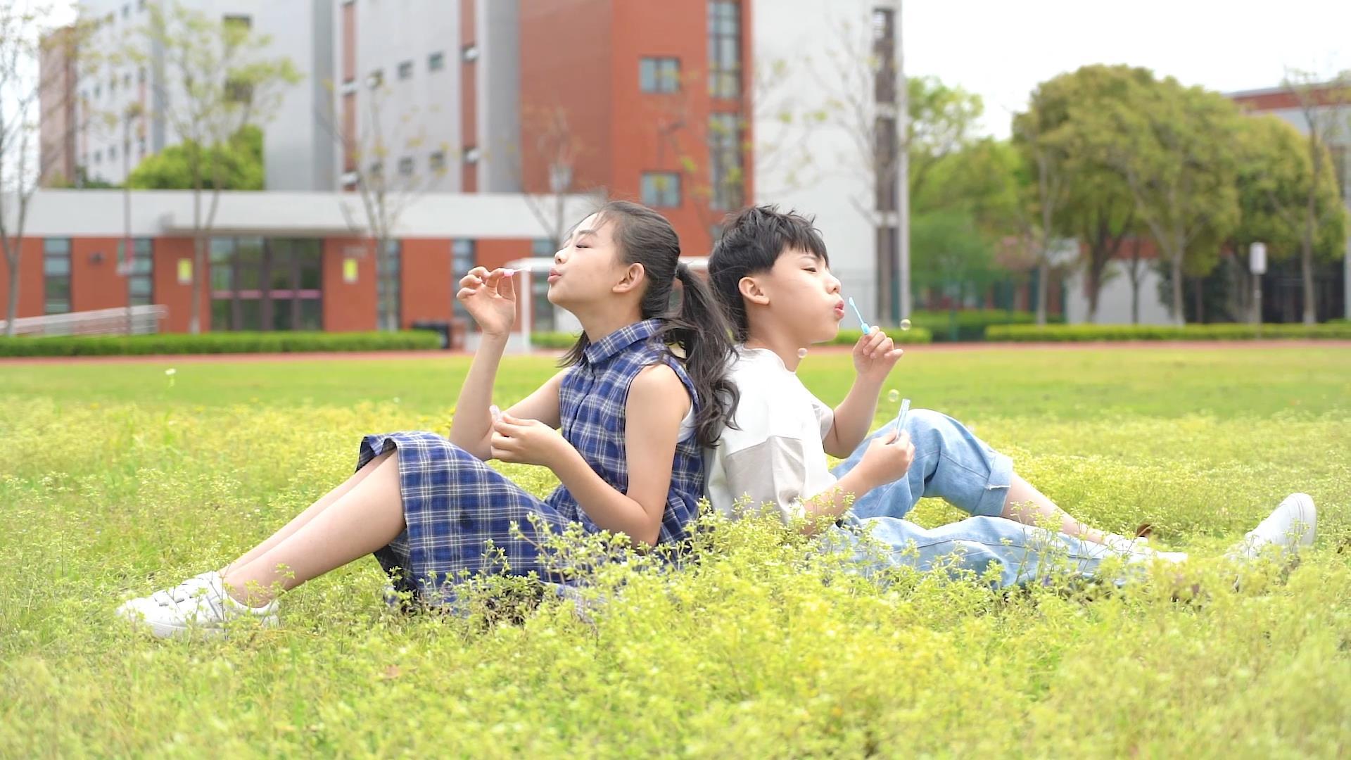 孩子们坐在草地上吹泡泡视频的预览图