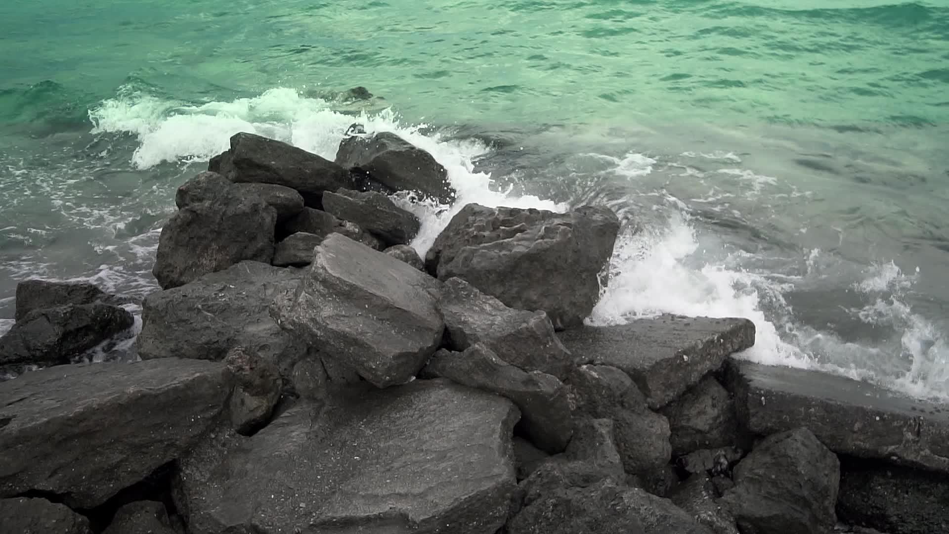 风浪慢慢地把石头喷到岩石海岸视频的预览图