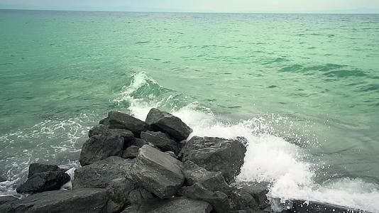 风浪慢慢地把石头喷到岩石海岸视频的预览图