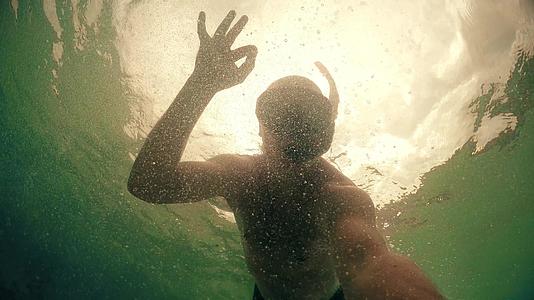 潮水男子戴着面具在海里潜水举起手来表示他的护身符视频的预览图