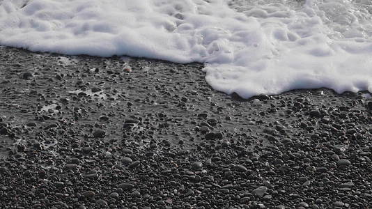 海浪和泡沫在鹅卵石海岸上滚动超慢运动近视视频的预览图