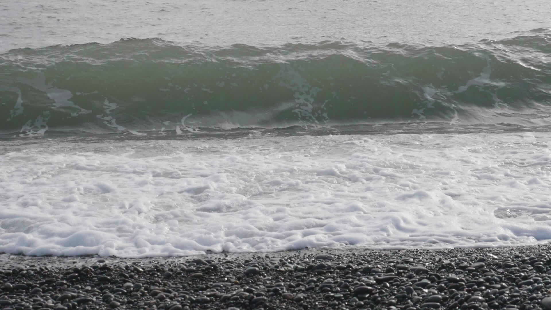 海浪喷洒泡沫和小石头的海岸超慢运动视频的预览图