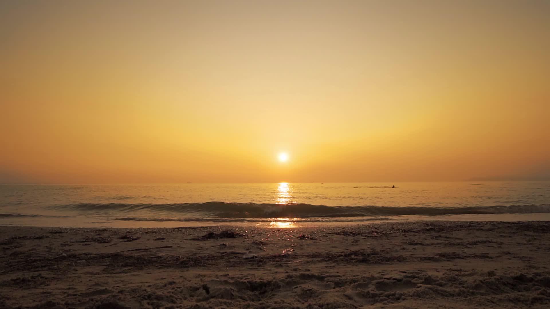 海浪的自然背景是太阳在日落时慢慢落到海滩海岸视频的预览图