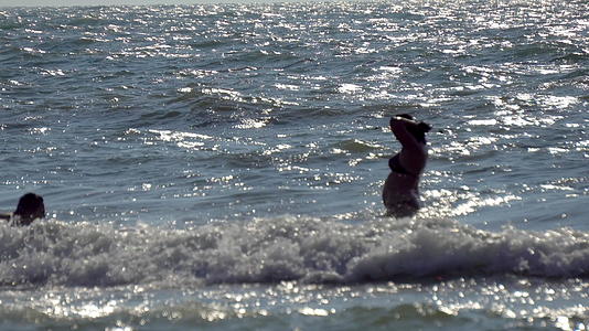 游客在粗海中洗澡在海滩上用大浪和慢动作放松视频的预览图