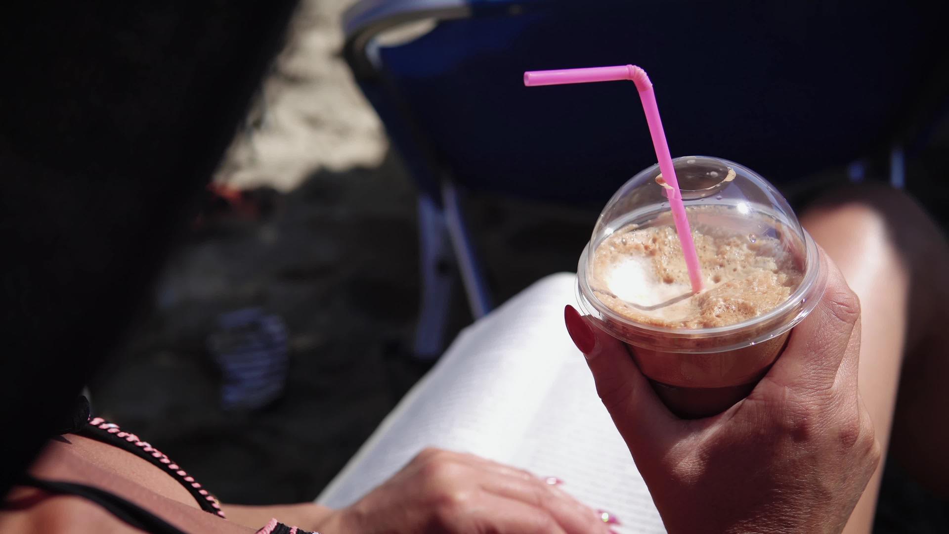 在海滩上喝酒frappe暑假期间的咖啡因和阅读视频的预览图