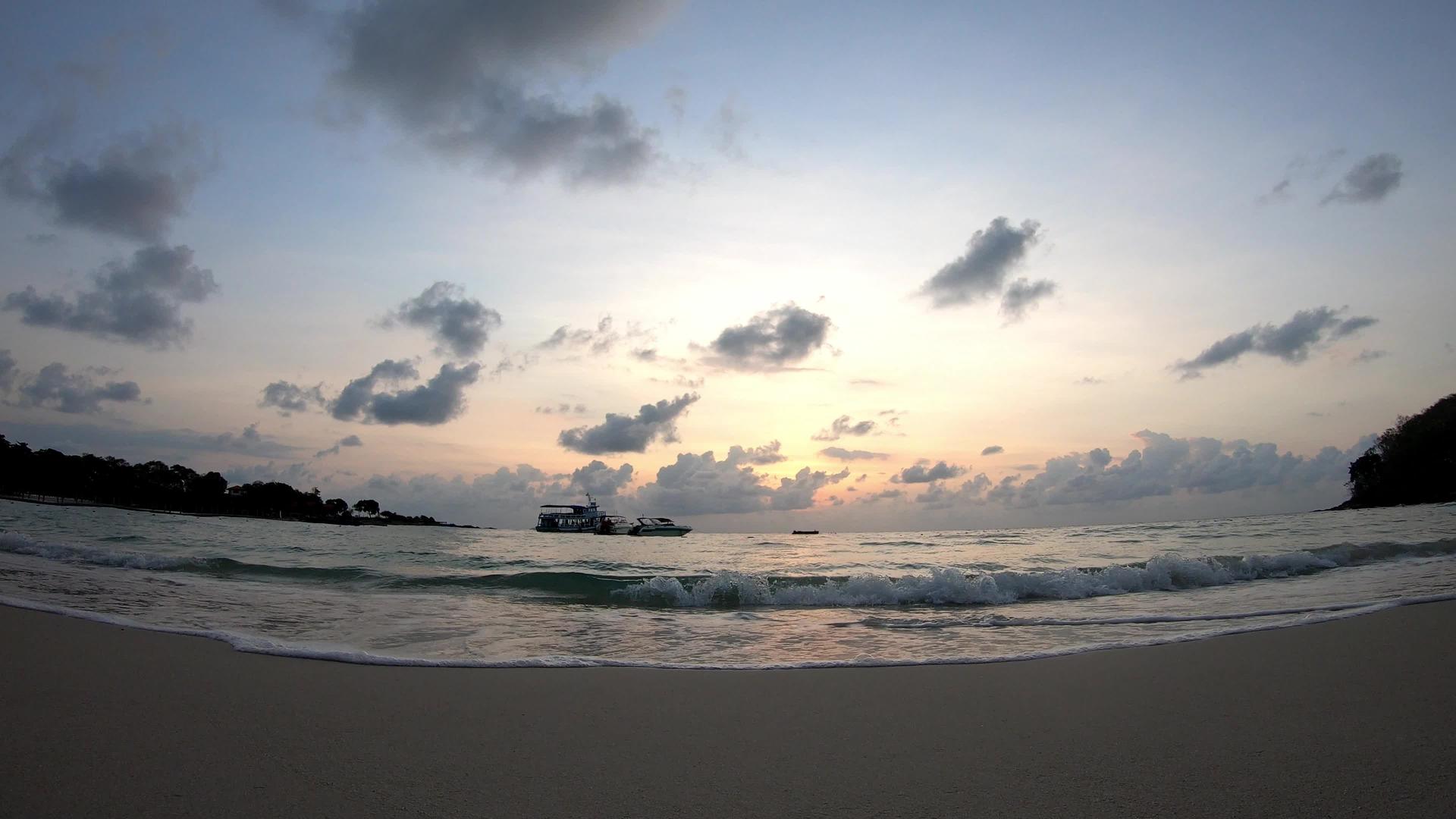 海浪撞击海滩船底部云层快速移动日出的金光照亮天空天空视频的预览图