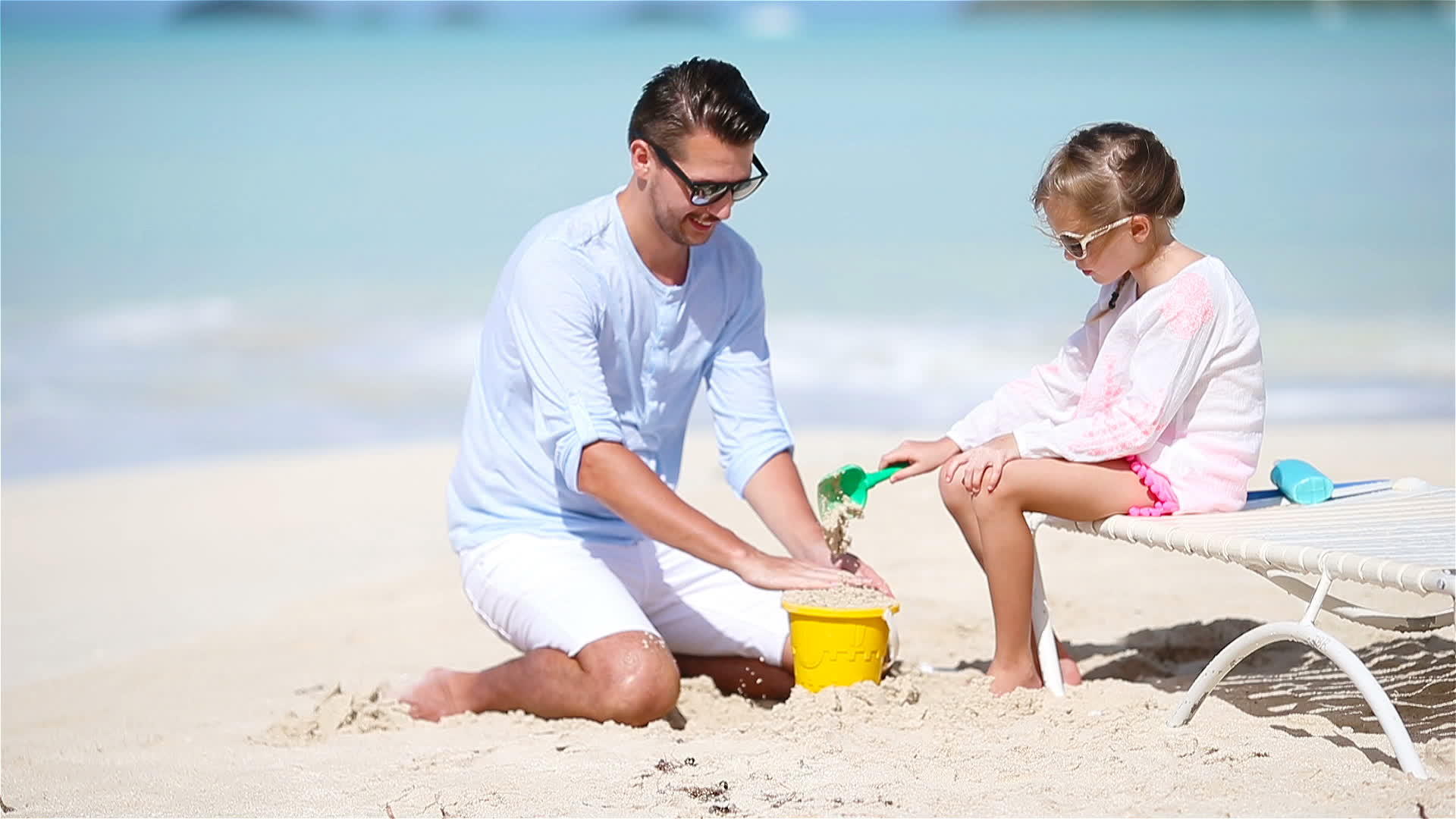 父亲和他的小女儿在热带海滩上玩沙子和沙堡视频的预览图