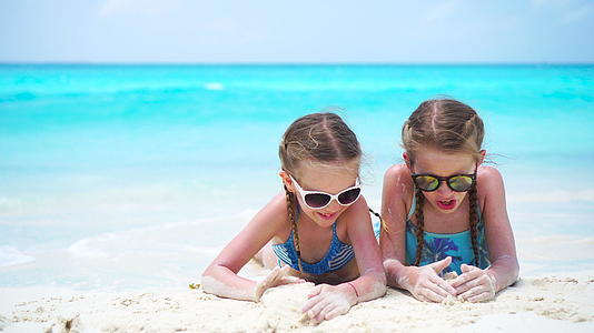 可爱的孩子在白色沙滩上玩沙子两个女孩在暑假玩得很开心视频的预览图