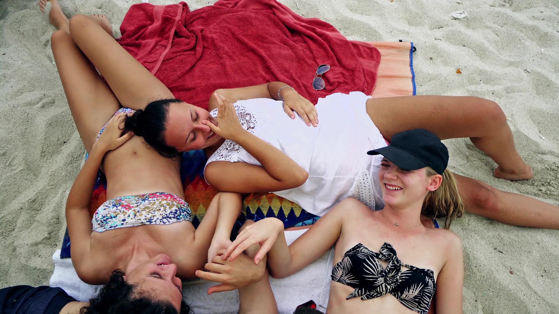 年轻人躺在沙滩上围着圆圈笑得很开心视频的预览图