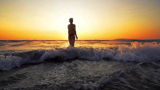 穿着比基尼的快乐女人在海里跳跃慢慢地移动视频的预览图