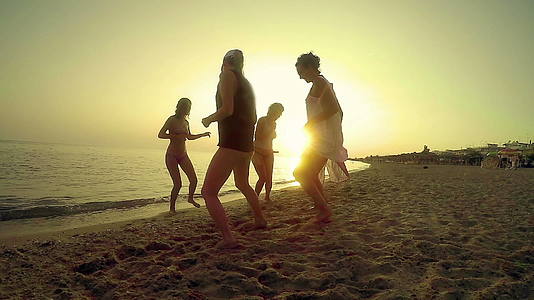 一群快乐的年轻人在海滩上跳舞...在美丽的夏日视频的预览图