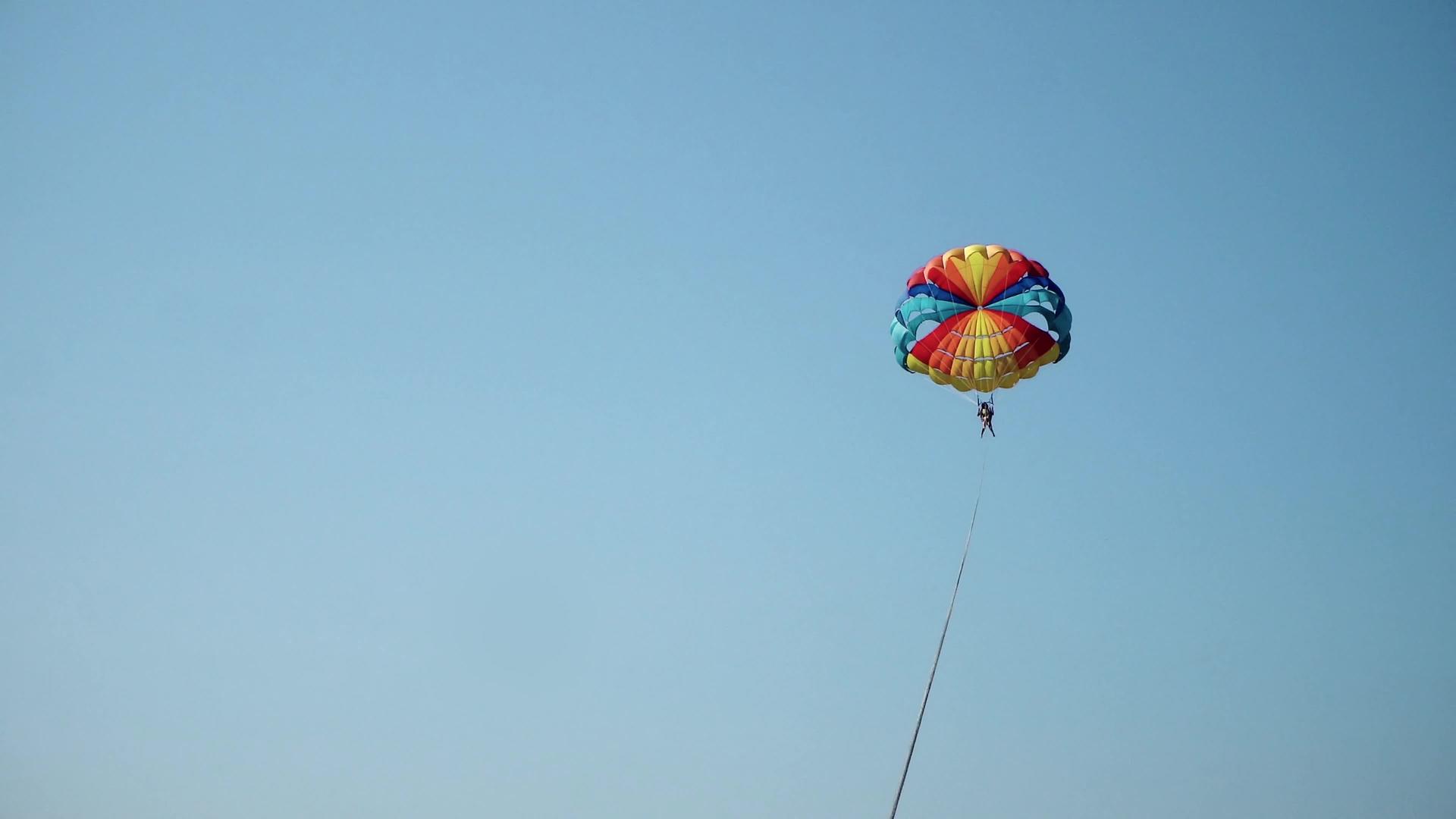 夏天快乐的夫妇在海滩上滑翔伞降落伞挂在半空中视频的预览图