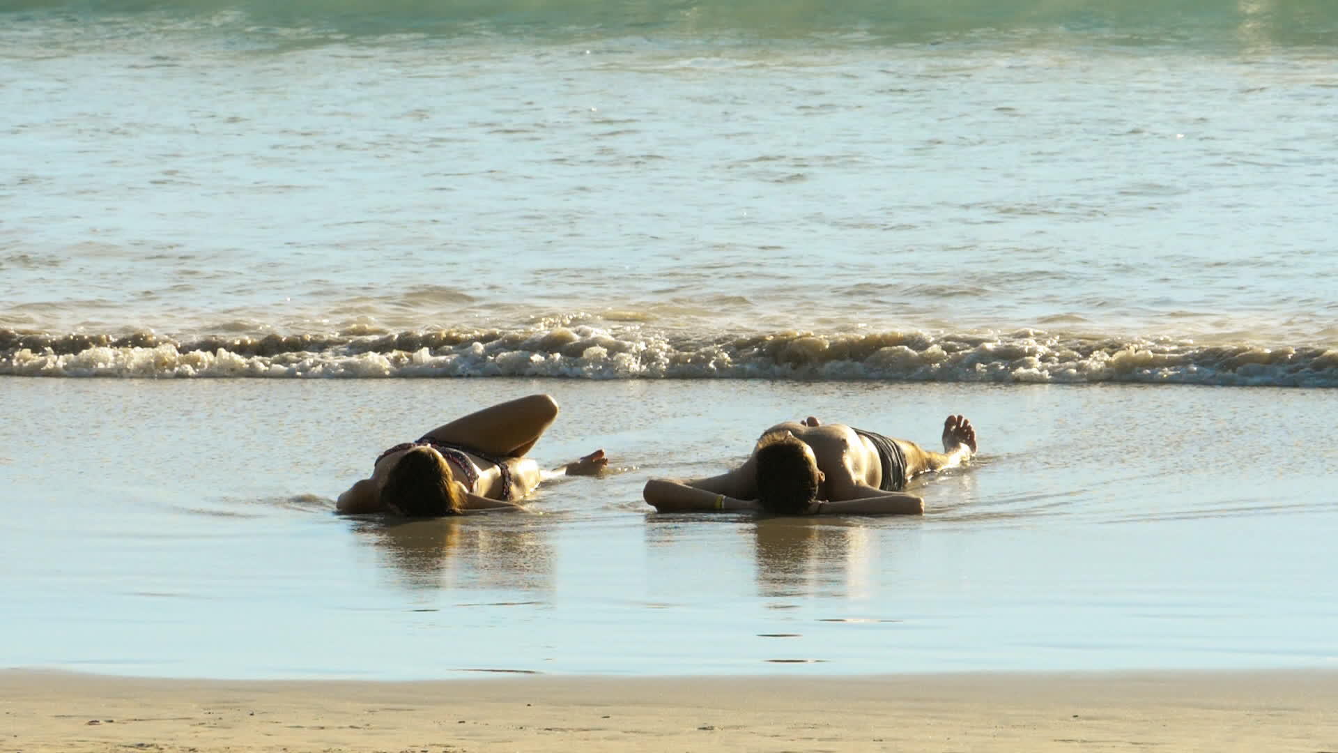 年轻夫妇躺在沙滩上的沙滩上视频的预览图