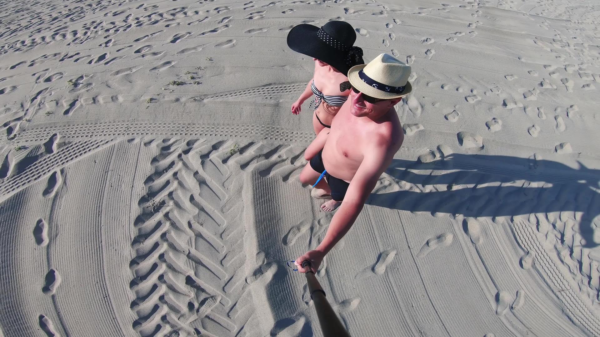 一对快乐的夫妇戴着帽子走在空荡荡的海滩上视频的预览图