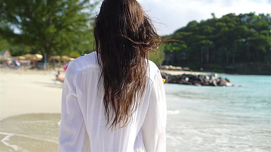 年轻美女在热带海岸玩得开心女孩们在白色的海滩上走来走去视频的预览图