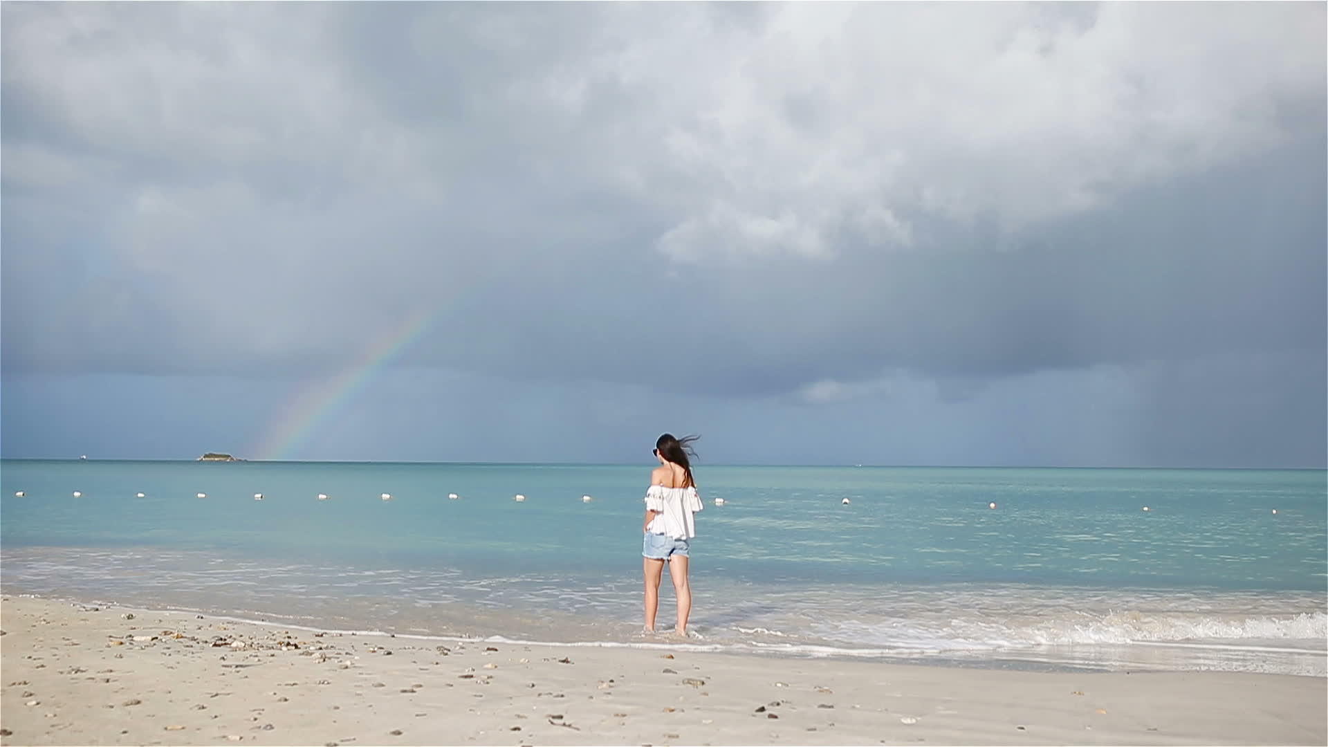 热带海滩上美丽的年轻女性和背景上的彩虹视频的预览图