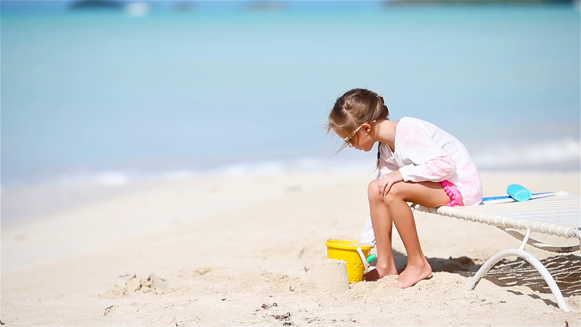 可爱的小女孩在海滩度假上玩玩具视频的预览图