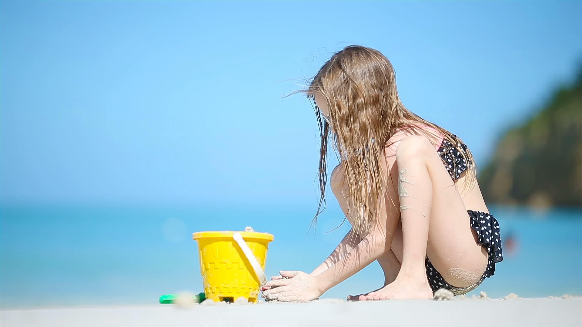可爱的小女孩在海滩度假时玩玩具视频的预览图