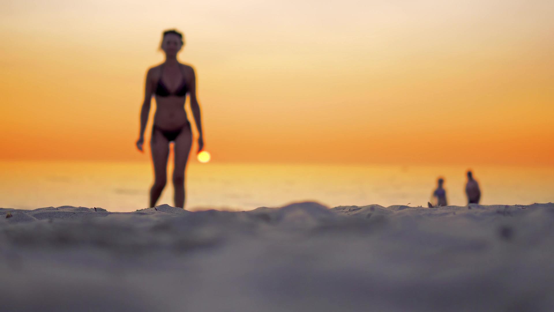 年轻的拉丁裔美国女孩在日落时走过海边视频的预览图