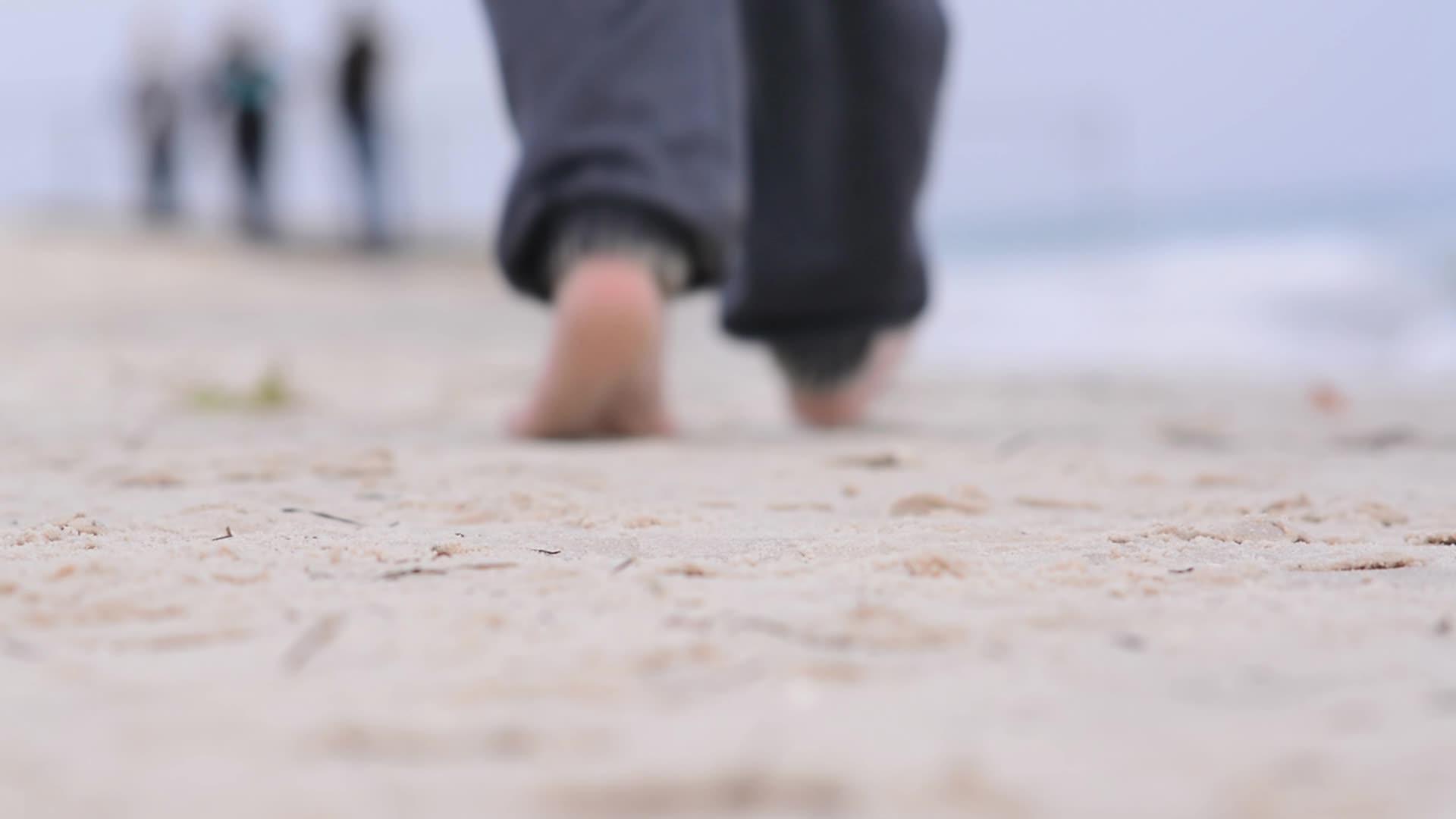 一个十几岁的男孩赤脚在海滩上散步视频的预览图