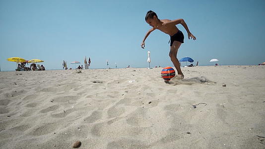 男孩在沙滩上玩雪球和踢足球视频的预览图