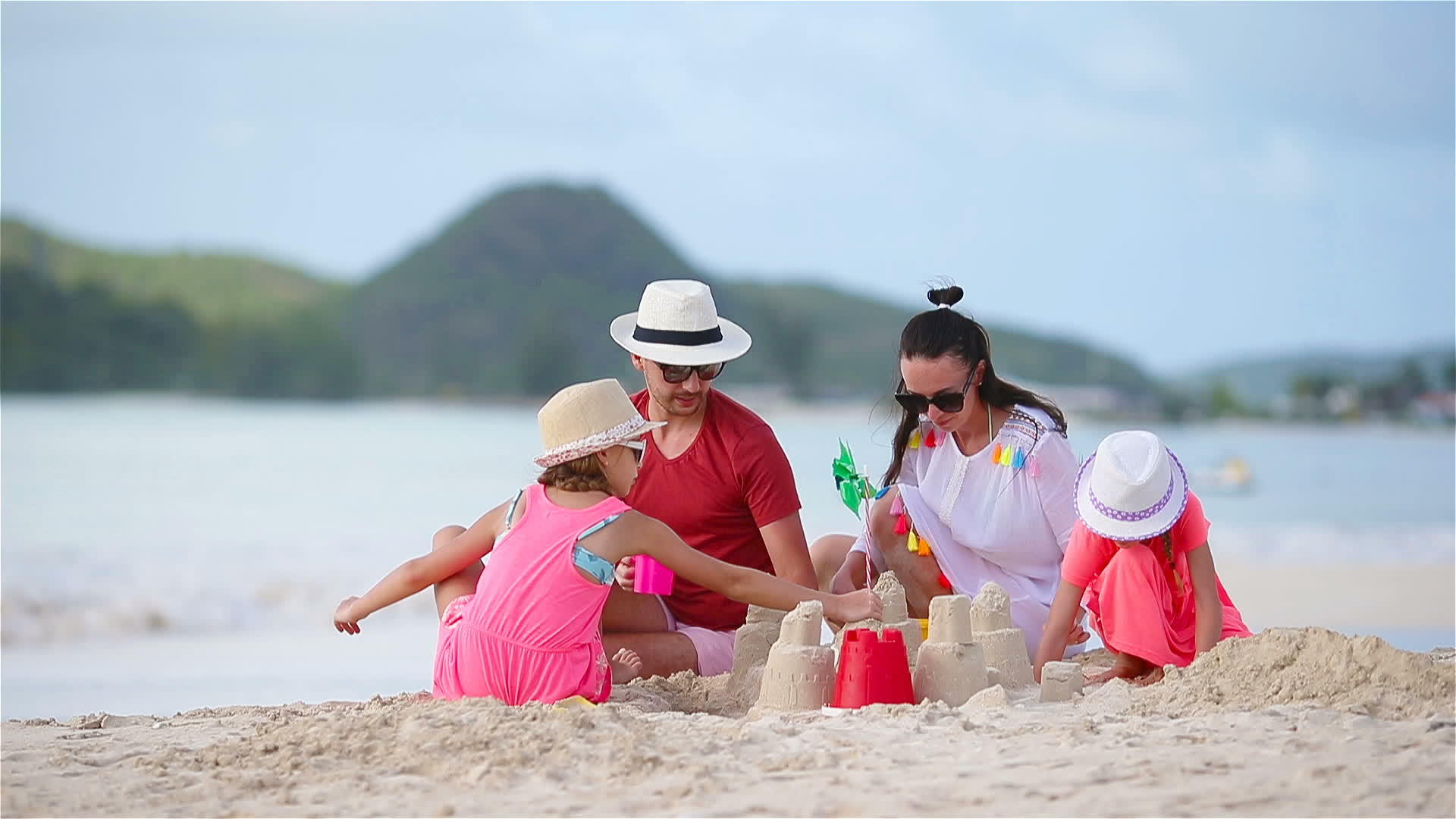 父母在热带白色沙滩上玩儿童沙堡游戏视频的预览图