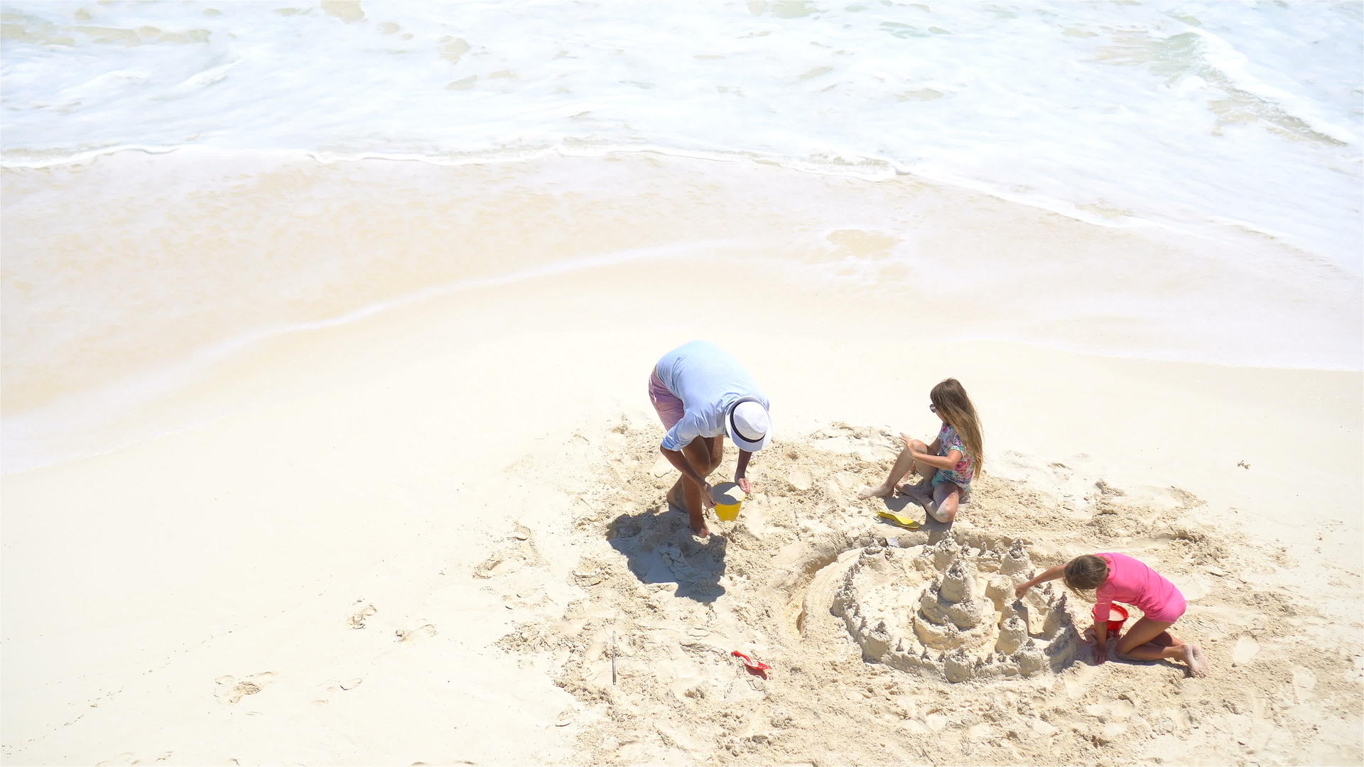 从上面看父亲和小女儿在热带海滩制作沙堡视频的预览图