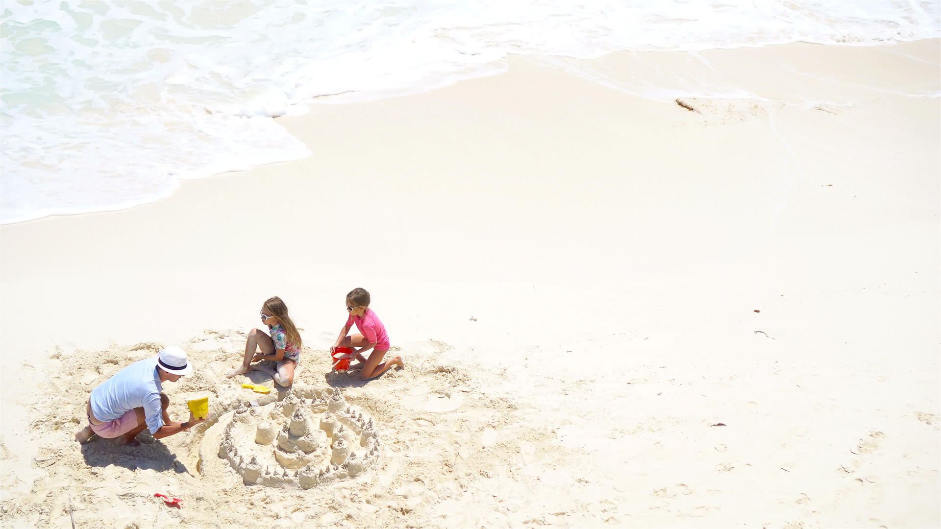 从上面看父亲和小女儿在热带海滩制作沙堡视频的预览图