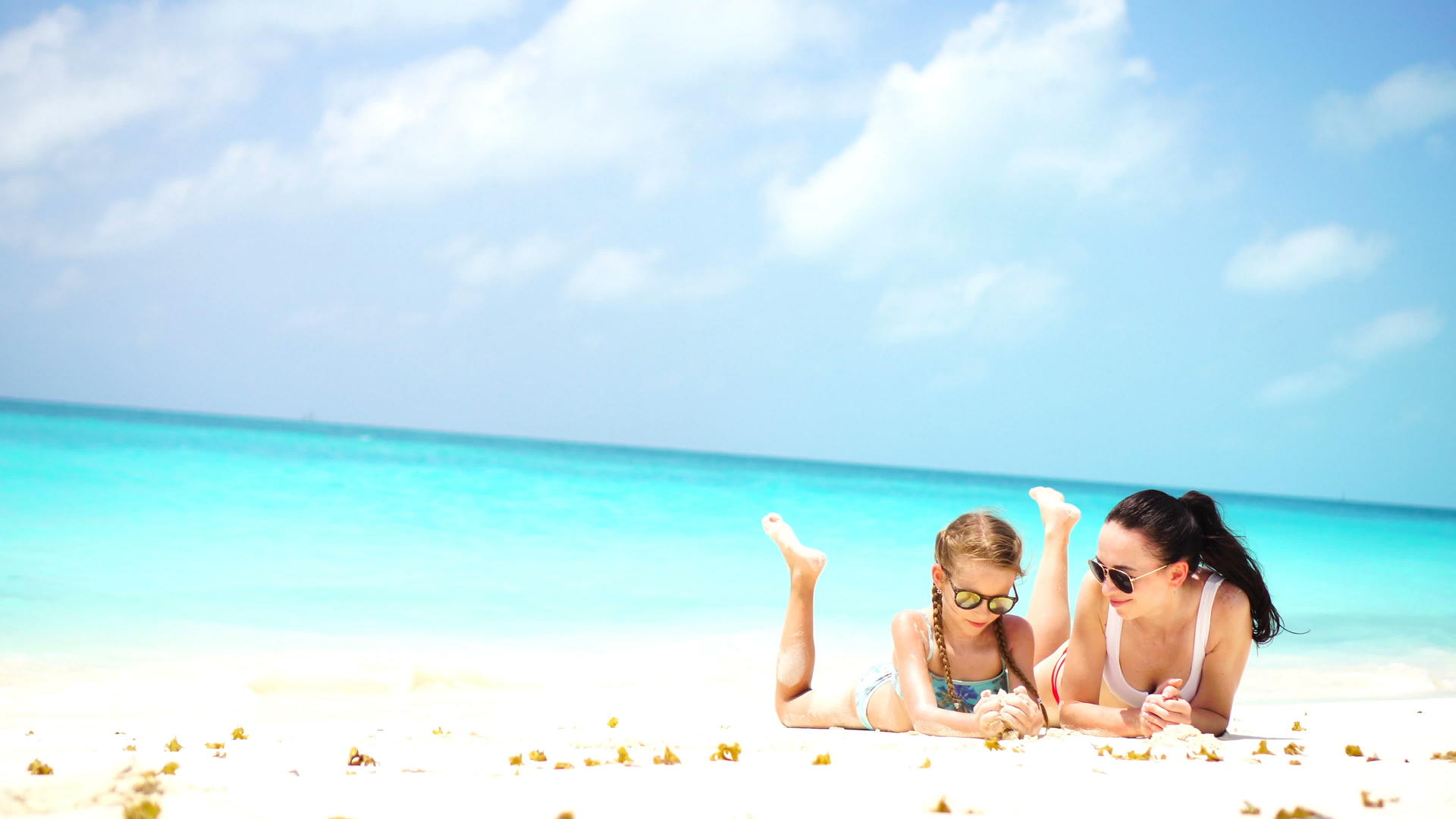 可爱的小女孩和年轻的母亲在热带海滩上视频的预览图