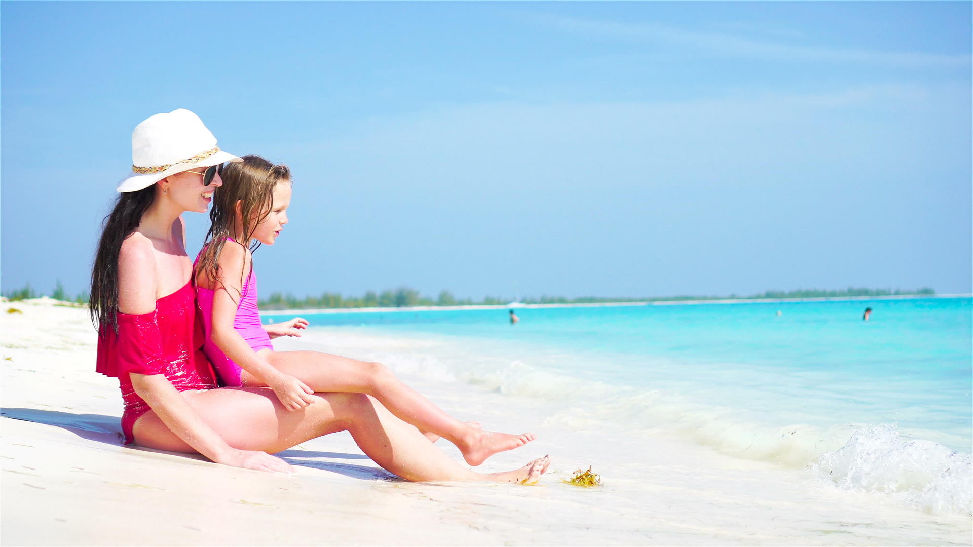 可爱的小女孩和年轻的母亲在热带海滩上视频的预览图