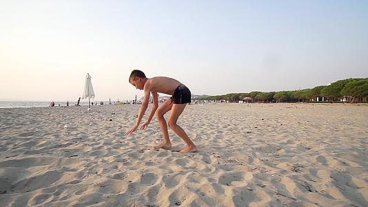 小男孩微笑的男孩跳上沙滩慢慢运动视频的预览图