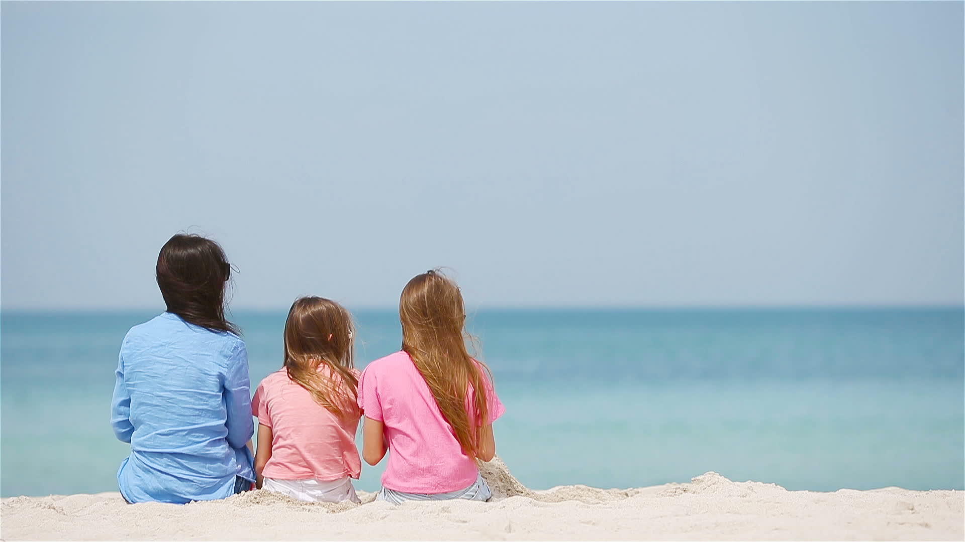 母亲和小女儿在热带海滩建造沙城堡视频的预览图