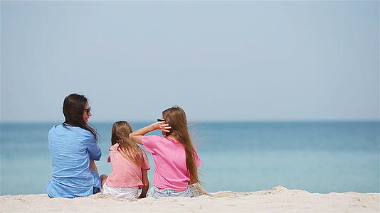 可爱的小女孩和年轻的母亲在热带白色沙滩上视频的预览图