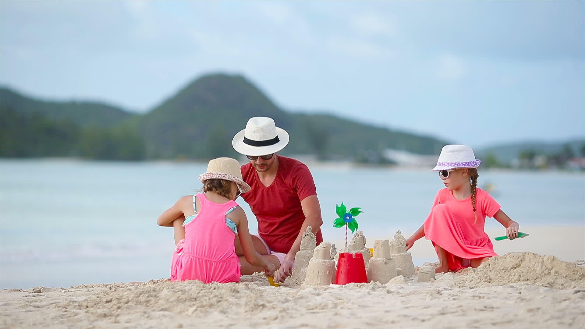 父亲和孩子在热带海滩上建造沙城堡视频的预览图