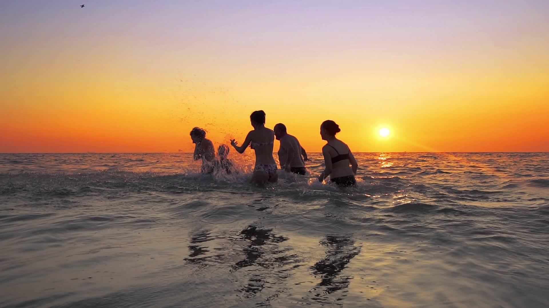 在海滩派对上玩喷雾游戏的人在日落慢动作视频的预览图