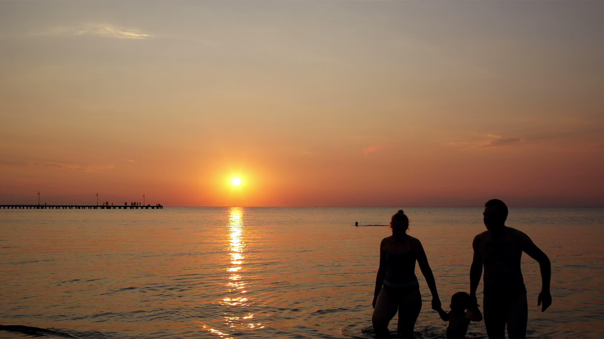 海滩上的年轻家庭在五颜六色的夕阳下视频的预览图