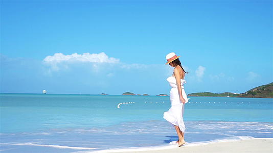 一个年轻的时尚女孩在海滩上戴着帽子视频的预览图