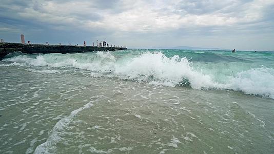 海滩上的海浪破碎背景有码头视频的预览图