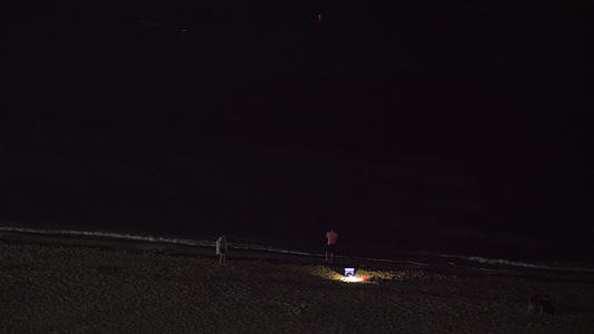 人们在海滩上放松看着黑暗的大海视频的预览图