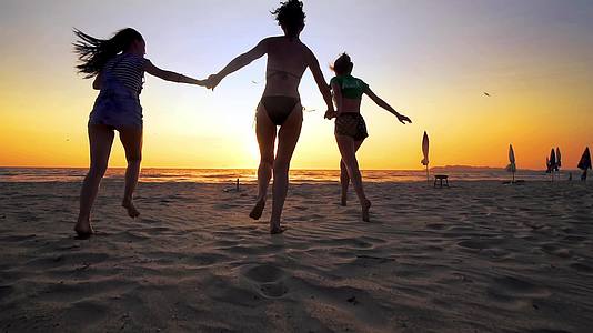 一群快乐的女朋友在日落时在海滩上跑来跑去视频的预览图