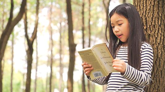 小女孩靠着树看书视频的预览图