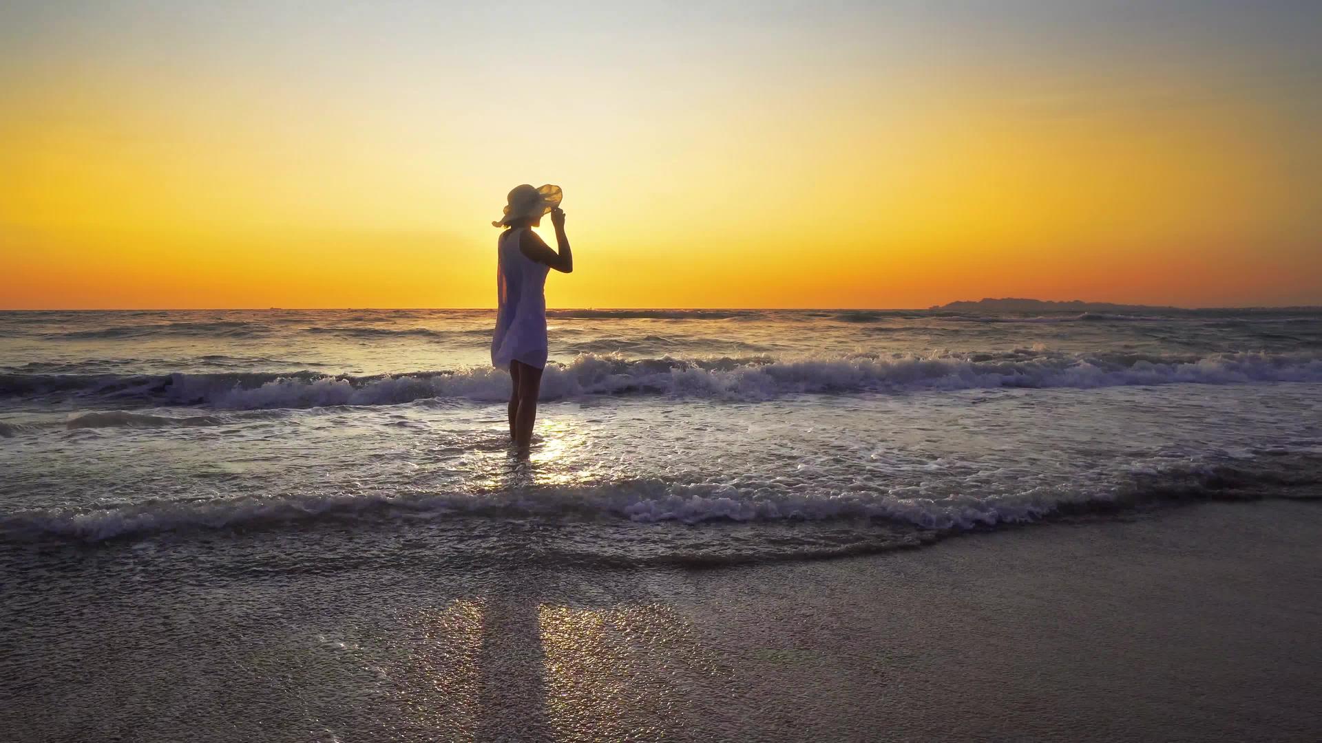 一个在日落时在海滩上微笑的自由和快乐的女人她在户外旅行假期视频的预览图