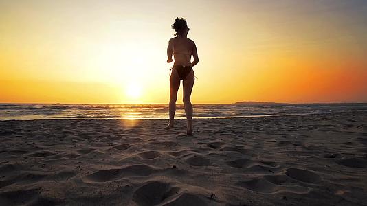 性感的黑发女人日落时在海滩上跑步电影慢动作视频的预览图