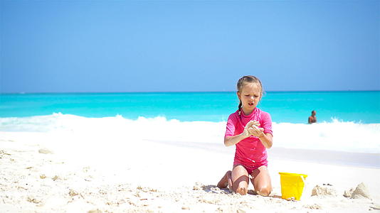 可爱的小女孩在白色沙滩上玩海滩玩具视频的预览图