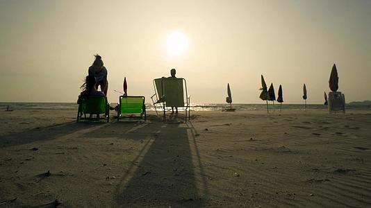 三个暑假的孩子坐在日出电影院的空沙滩椅子上视频的预览图