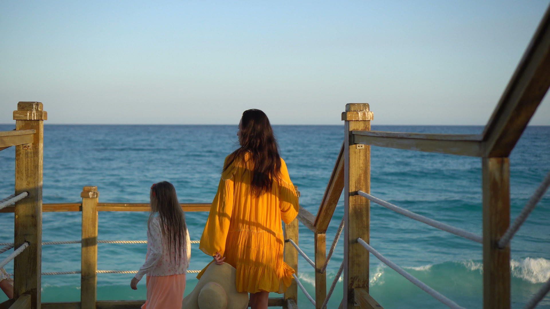 可爱的小女孩和年轻的母亲晚上在白色海滩上散步视频的预览图